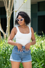 Black women  wearing a White Ribbed Body Suit and high waist shorts and white cat eye sunglasses